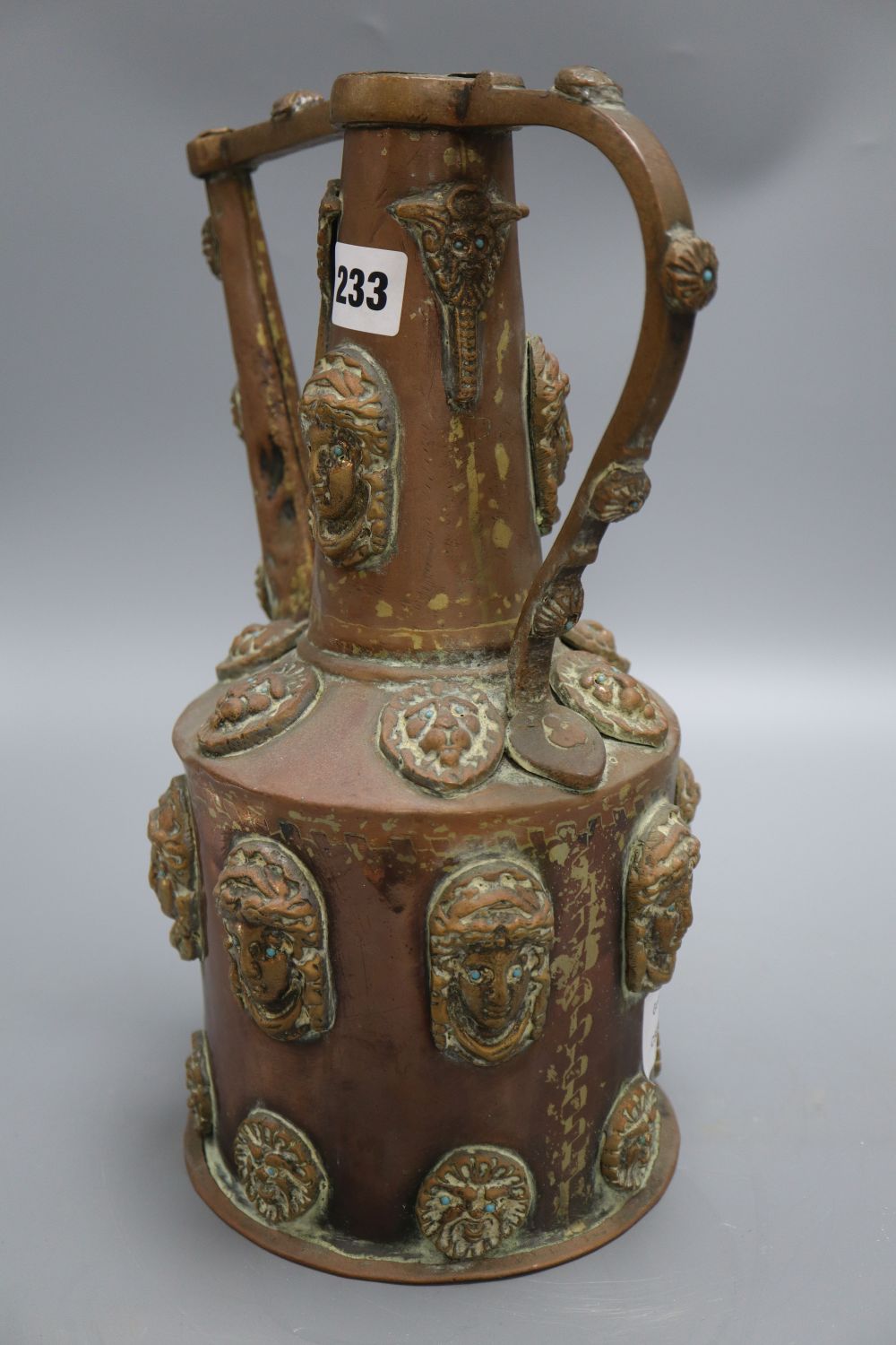 A Middle Eastern copper pot, decorated with classical ladies and lions faces with turquoise beaded eyes, height 32cm